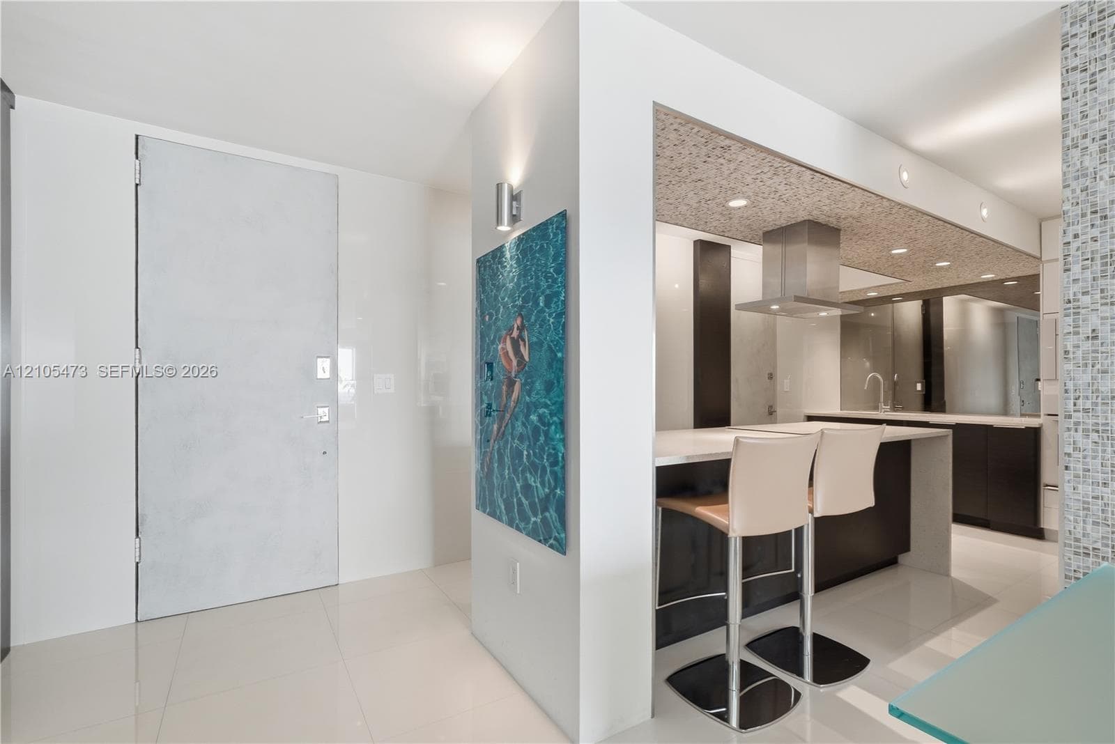 Kitchen featuring a stainless steel range hood, recessed lighting, dark cabinetry, a breakfast bar, and tile flooring
