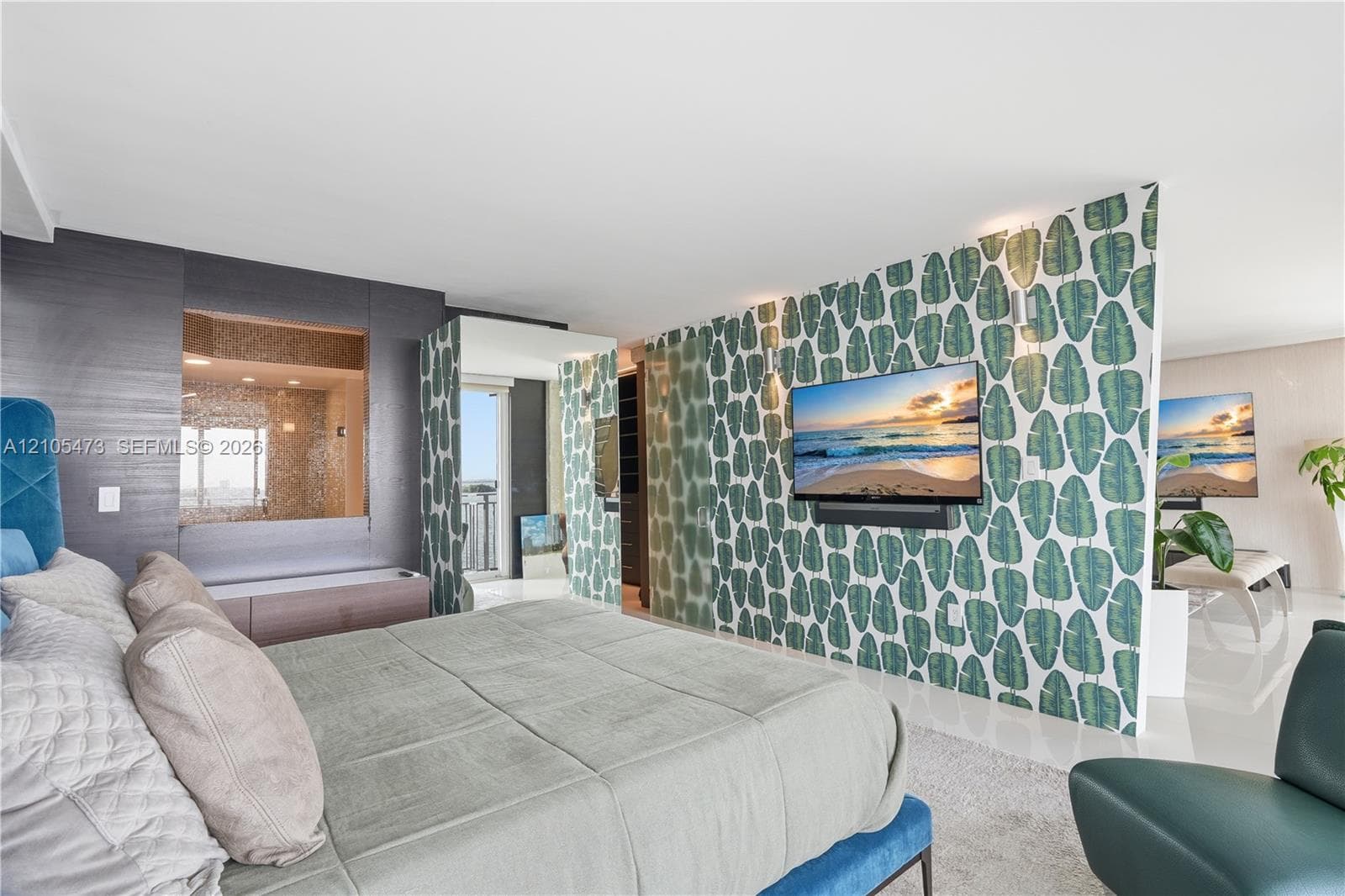 Integrated wall-mounted television, textured accent wall with built-in niche, patterned room divider, tiled shower enclosure, and light-colored flooring