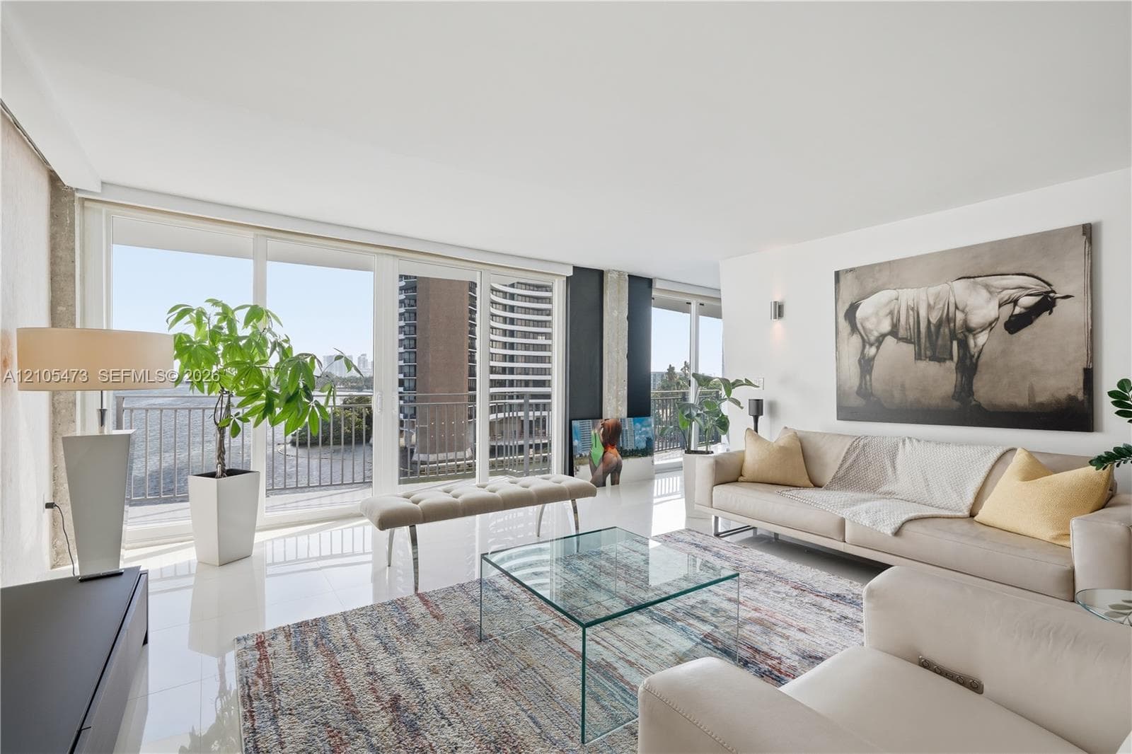 White high-gloss flooring, extensive sliding glass doors, balcony access, recessed lighting, and wall-mounted sconces