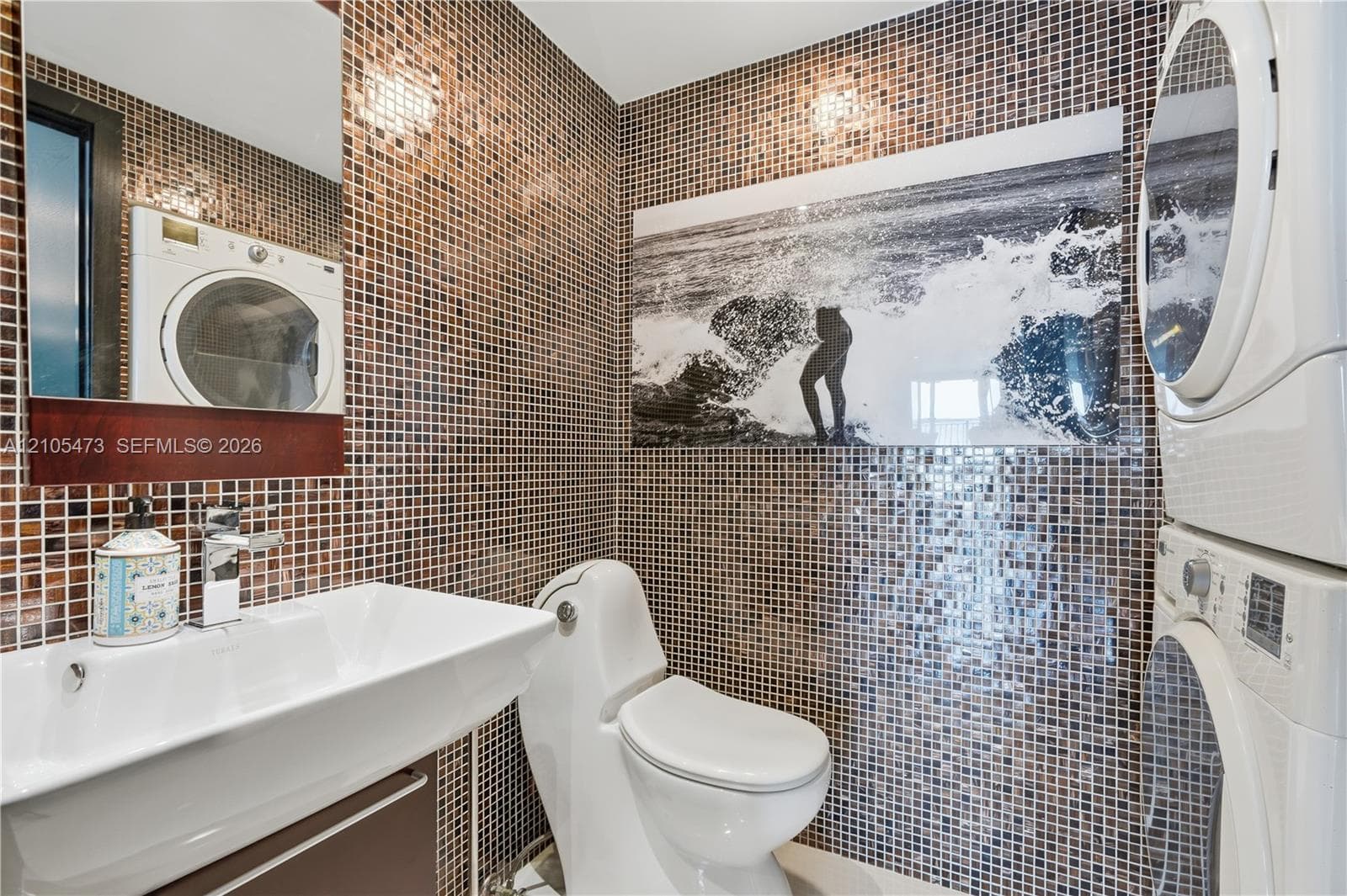 Mosaic tiled walls with a white rectangular sink, chrome faucet, and built-in mirror