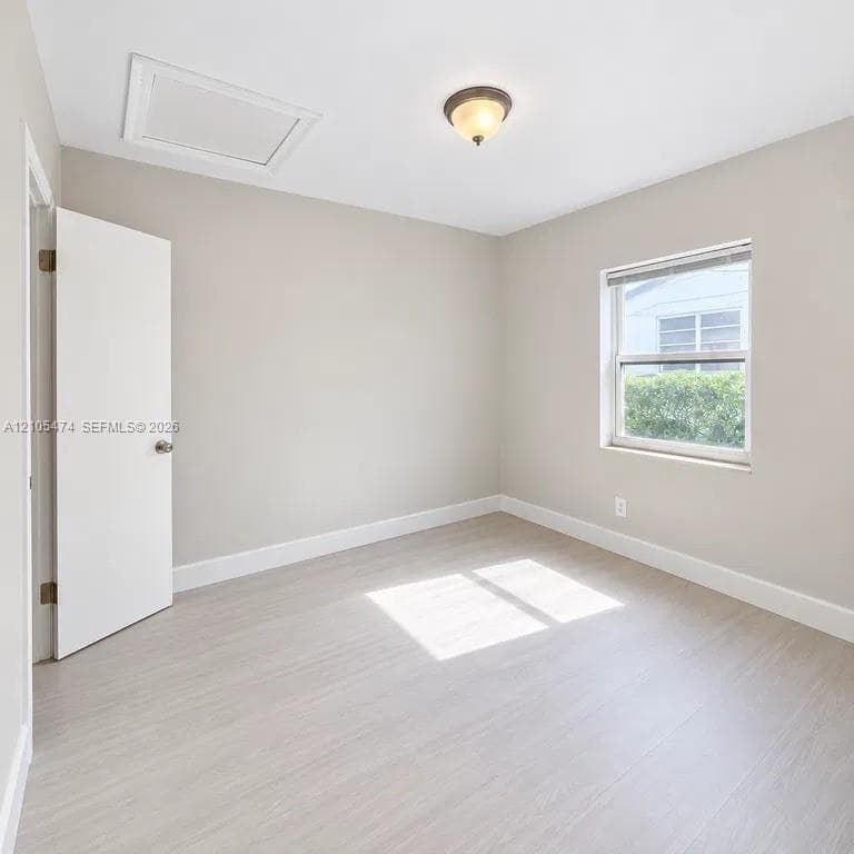 Light wood-finish flooring with white trim, neutral wall paint, and a semi-flush mount ceiling light
