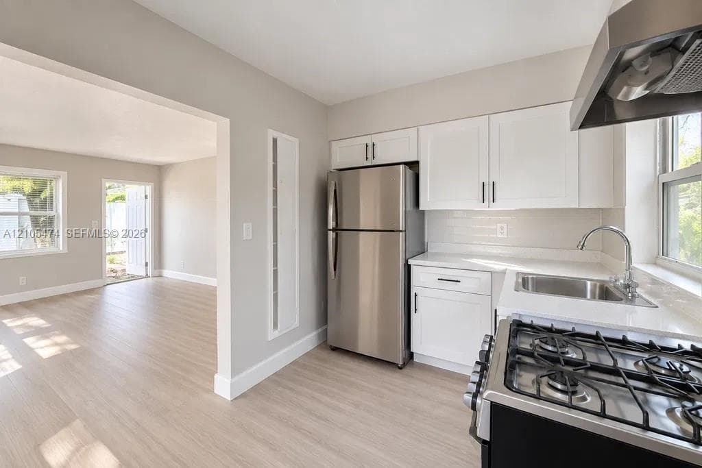 Kitchen featuring white cabinetry, stainless steel appliances, white subway tile backsplash, and light-toned countertops