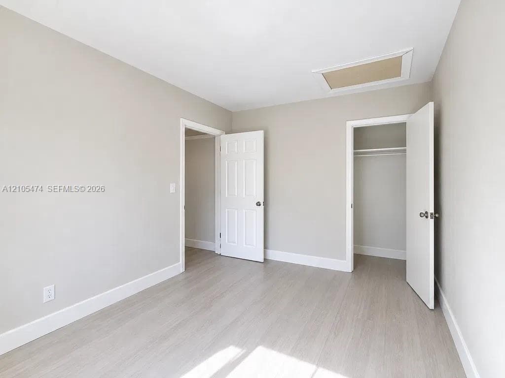 Light wood-finish flooring, neutral wall tones, white trim, and a ceiling access panel