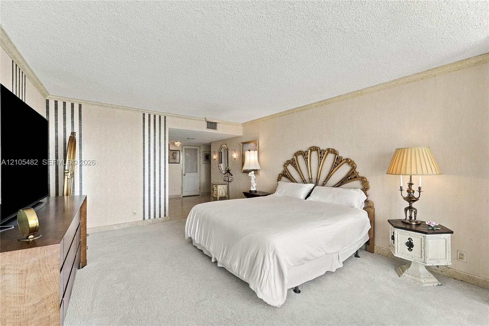 Spacious room featuring vertical striped wall treatments, neutral carpeting, textured ceiling, and crown molding