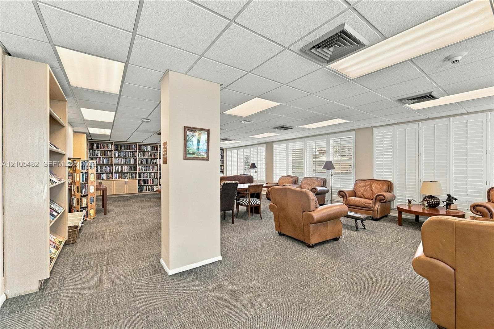Built-in floor-to-ceiling shelving, neutral carpet flooring, drop ceiling with integrated lighting, and plantation shutters