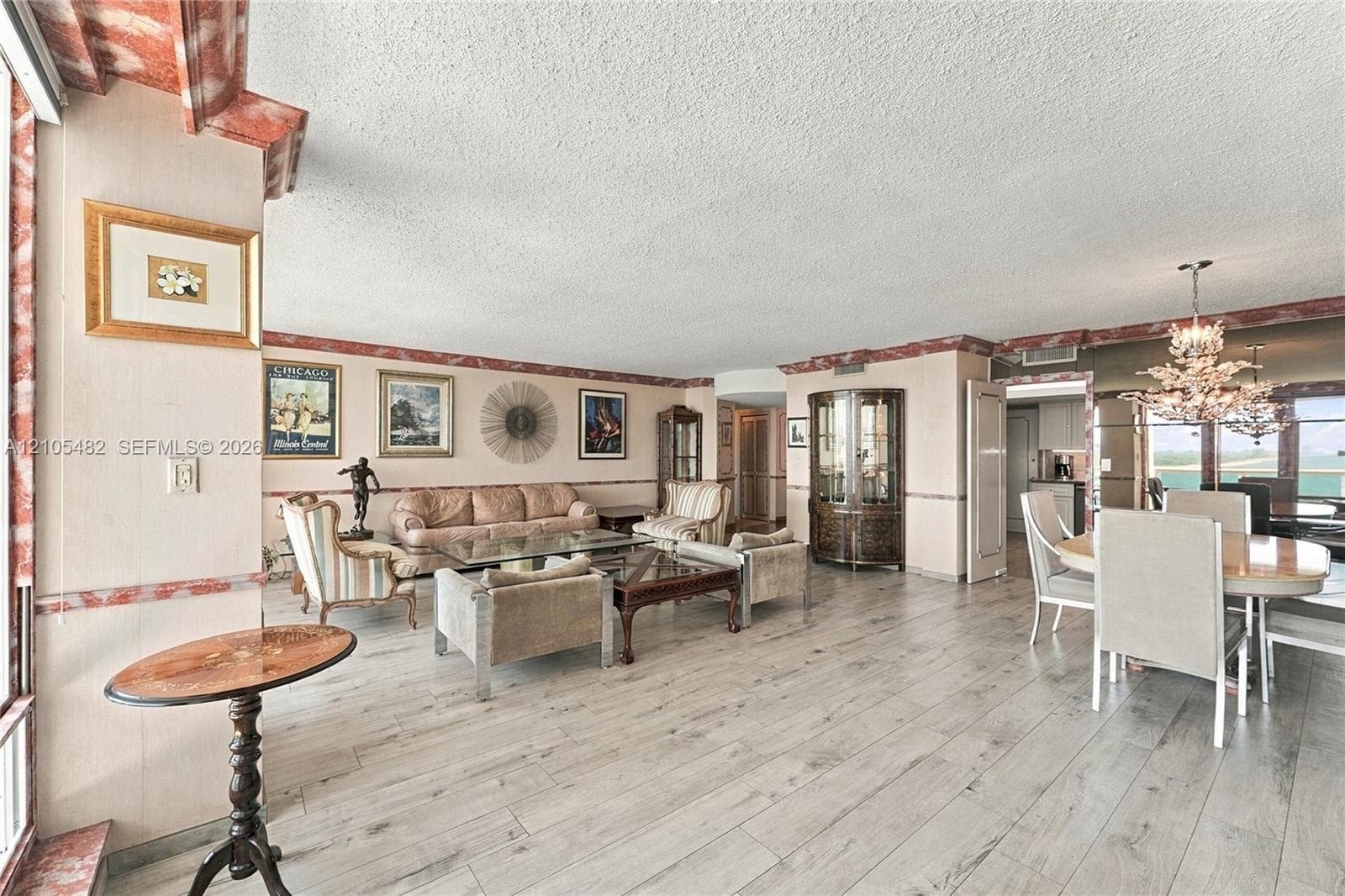 Open-concept interior featuring wood-finish flooring, decorative crown and chair rail molding, built-in display cabinetry, and a tiered crystal chandelier