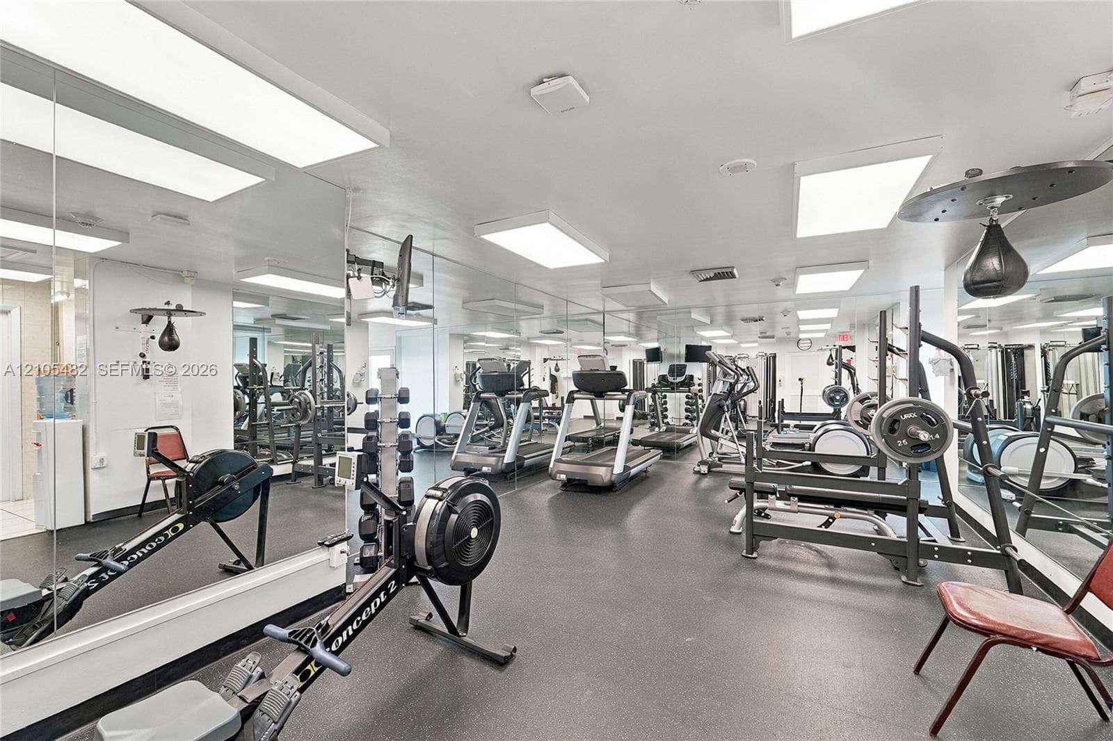 Fitness facility featuring extensive wall-to-wall mirrors, durable rubberized flooring, and multiple recessed LED lighting fixtures