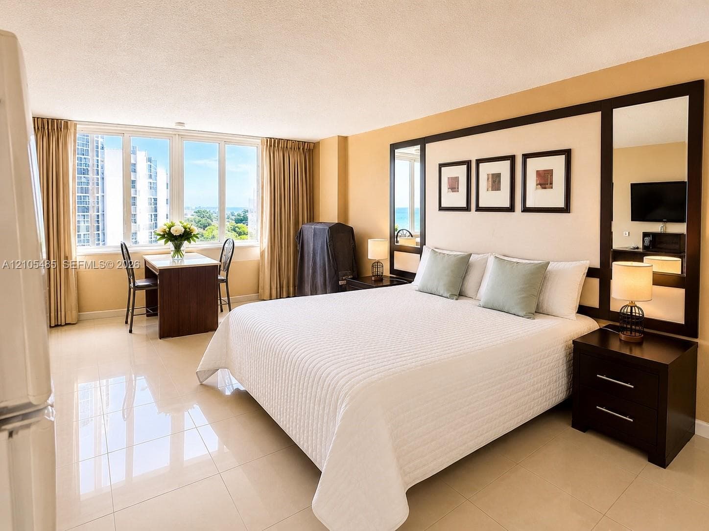 Expansive window offering abundant natural light, large format tile flooring, built-in headboard wall feature, integrated mirrors, and recessed lighting