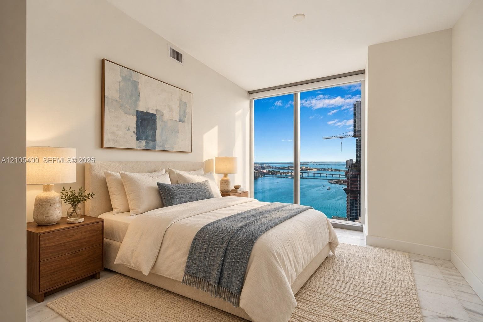 Floor-to-ceiling windows featuring panoramic water and city scenery, combined with neutral interior walls and stone-finish flooring