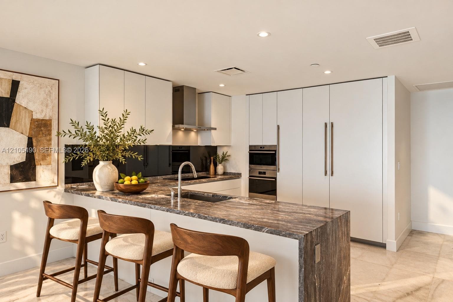 Kitchen featuring flat-panel cabinetry, a waterfall-edge stone countertop, integrated stainless steel appliances, a stainless steel range hood, and a dark-toned reflective backsplash