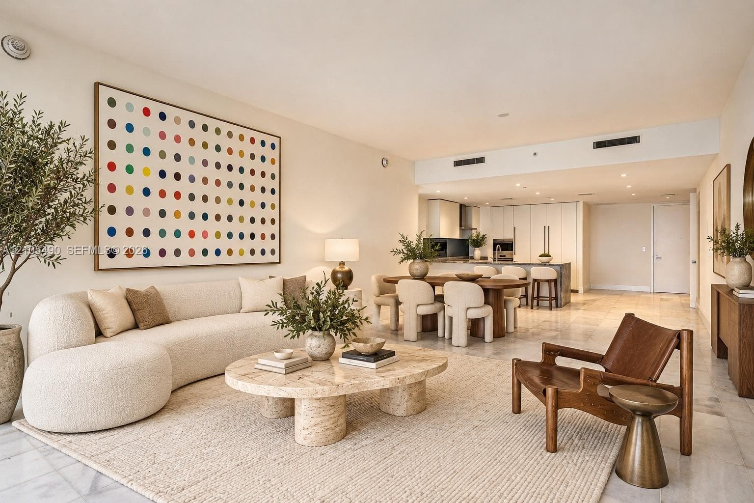 Open-concept interior featuring light-toned stone flooring, high ceilings with recessed lighting, and a modern kitchen with cabinetry and a center island