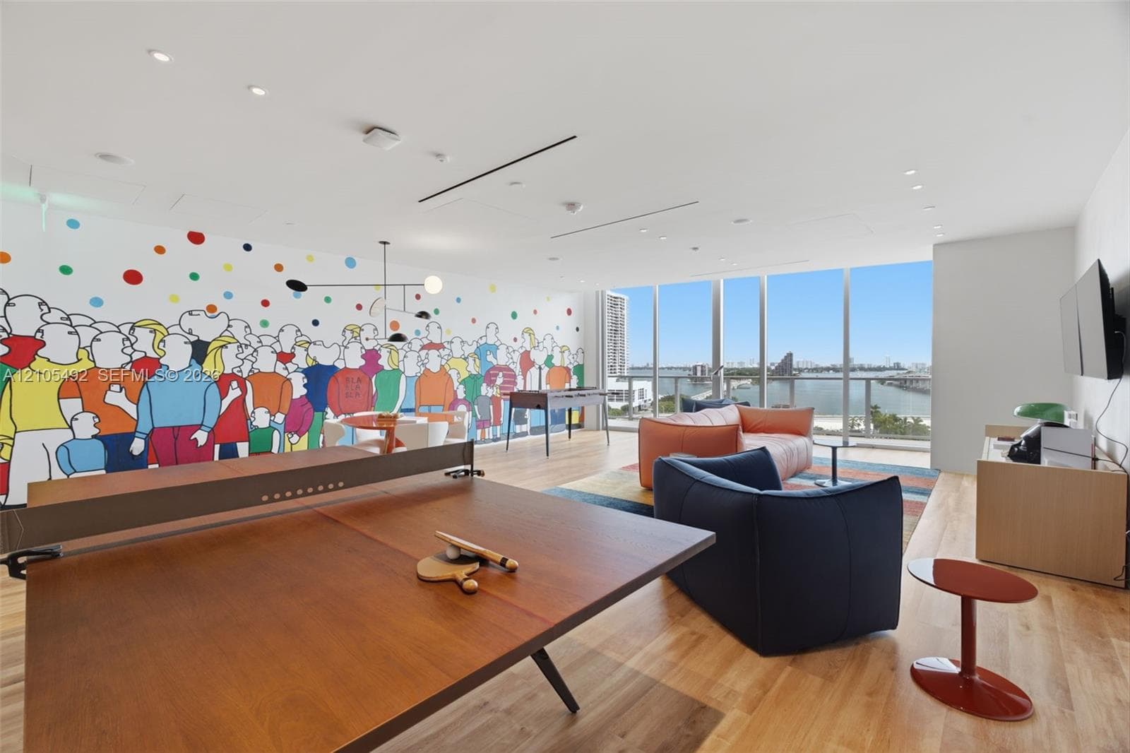 Floor-to-ceiling windows, wood-finish flooring, recessed lighting, and mural-accented wall