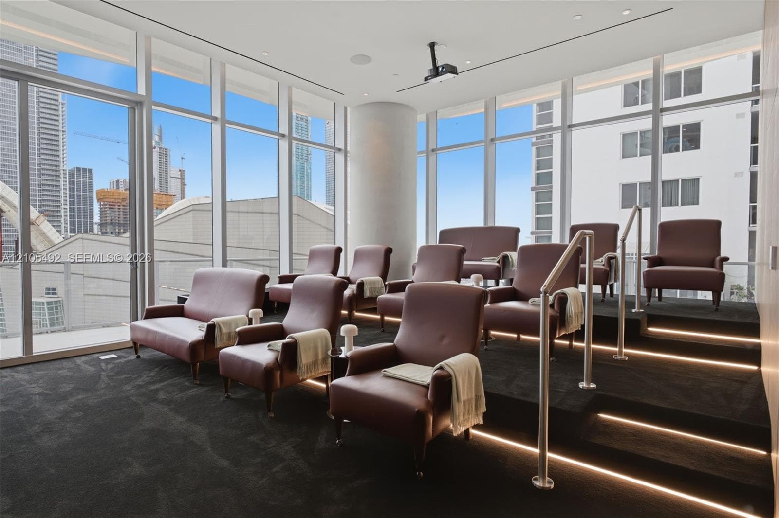 Floor-to-ceiling windows, tiered seating platform, integrated LED stair lighting, and ceiling-mounted projection hardware
