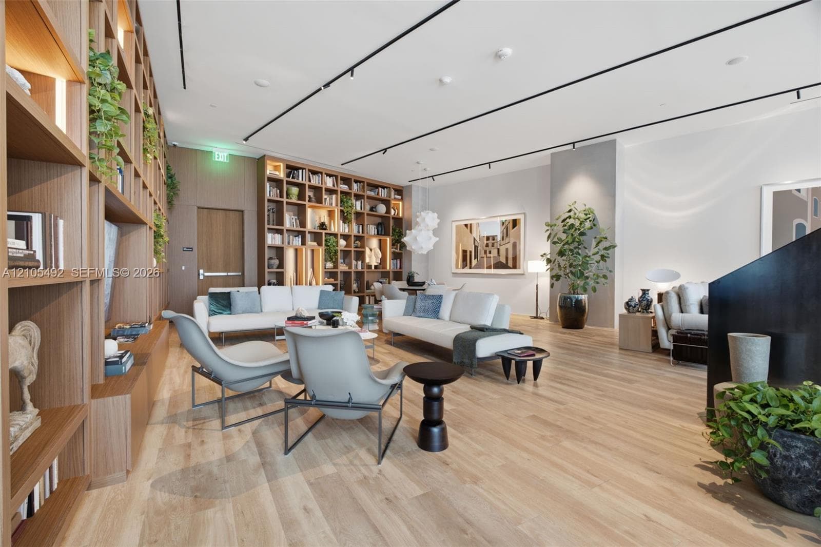 Full-height wall-to-wall built-in wood shelving, wood-finish flooring, and recessed track lighting