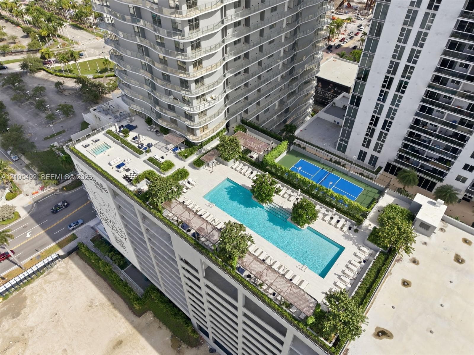 Rooftop amenity deck featuring a swimming pool, lap pool, tennis court, pergolas, and landscaped green space
