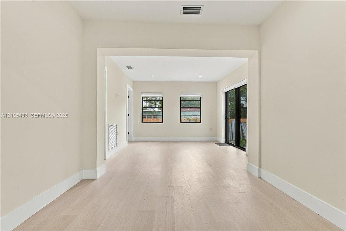 Interior space featuring wood-finish flooring, recessed lighting, and sliding glass doors with black frames