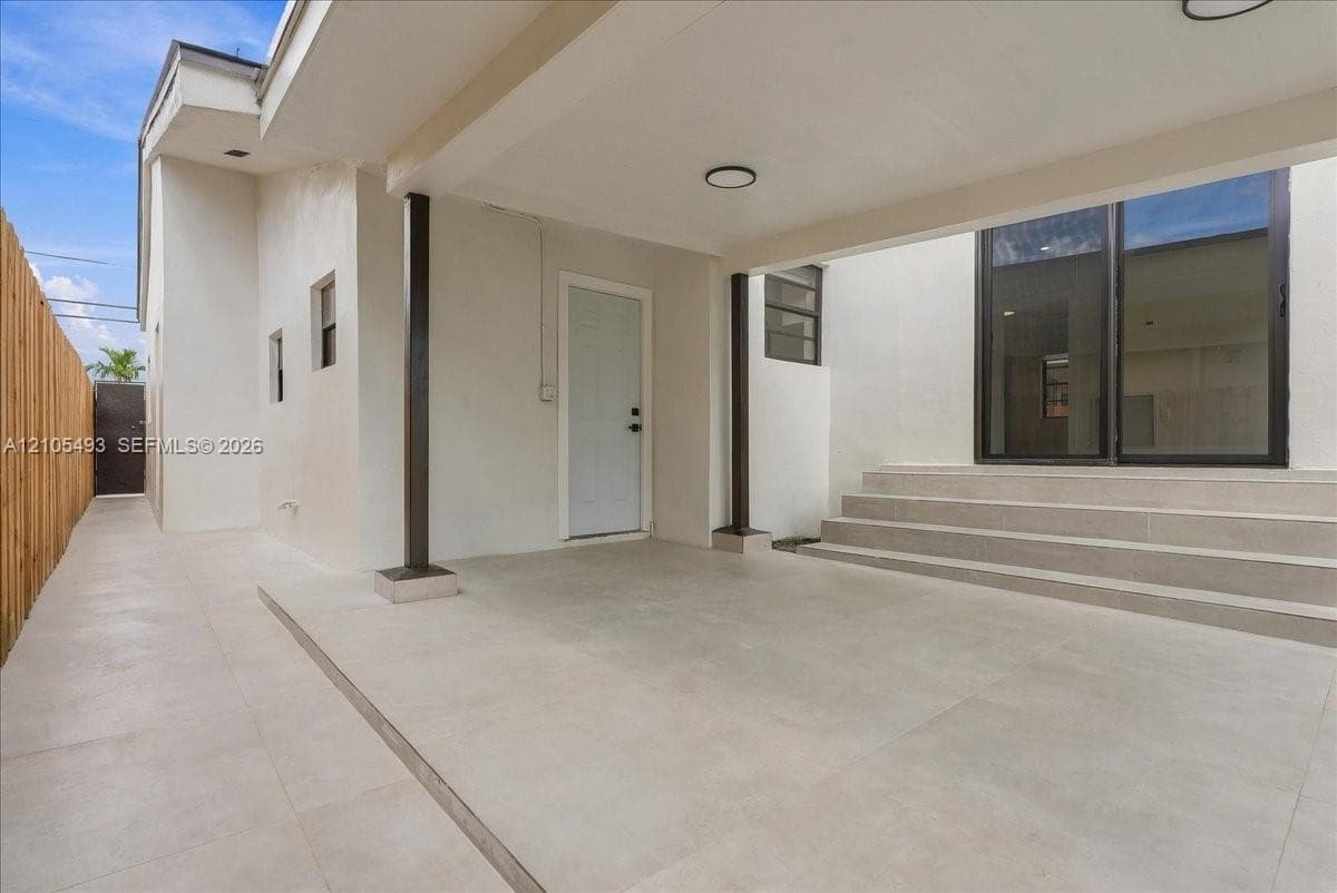 Covered patio featuring large-format porcelain tile flooring, recessed lighting, and sliding glass doors leading to concrete steps