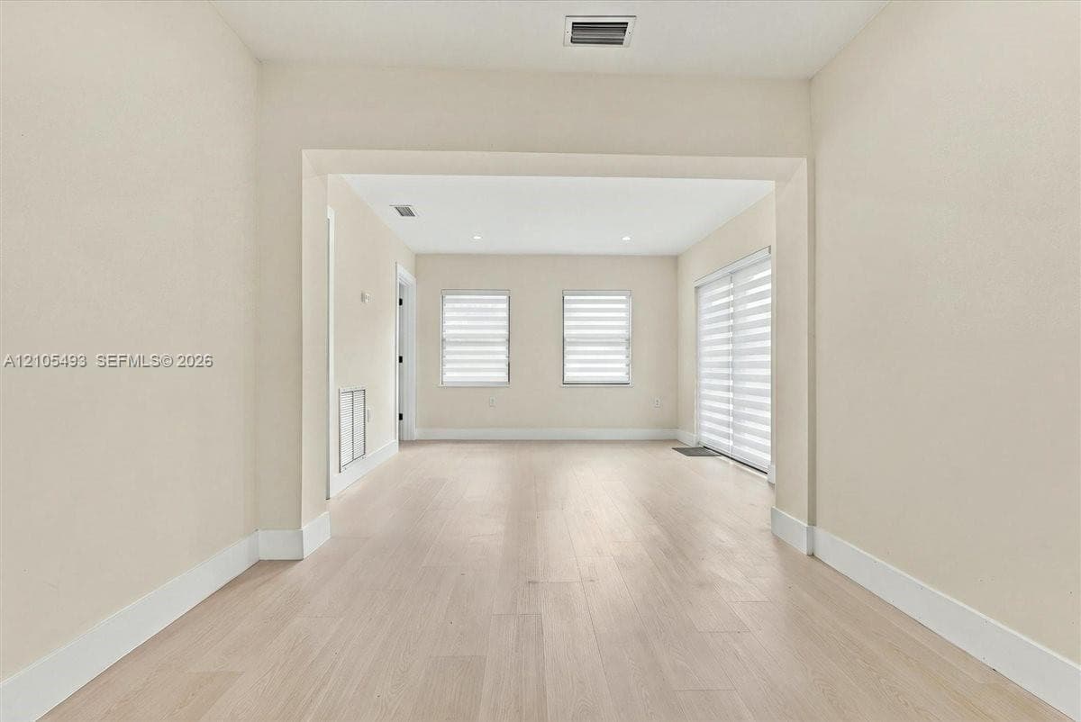 Interior space featuring wood-finish flooring, recessed lighting, and multi-paned windows with horizontal blinds