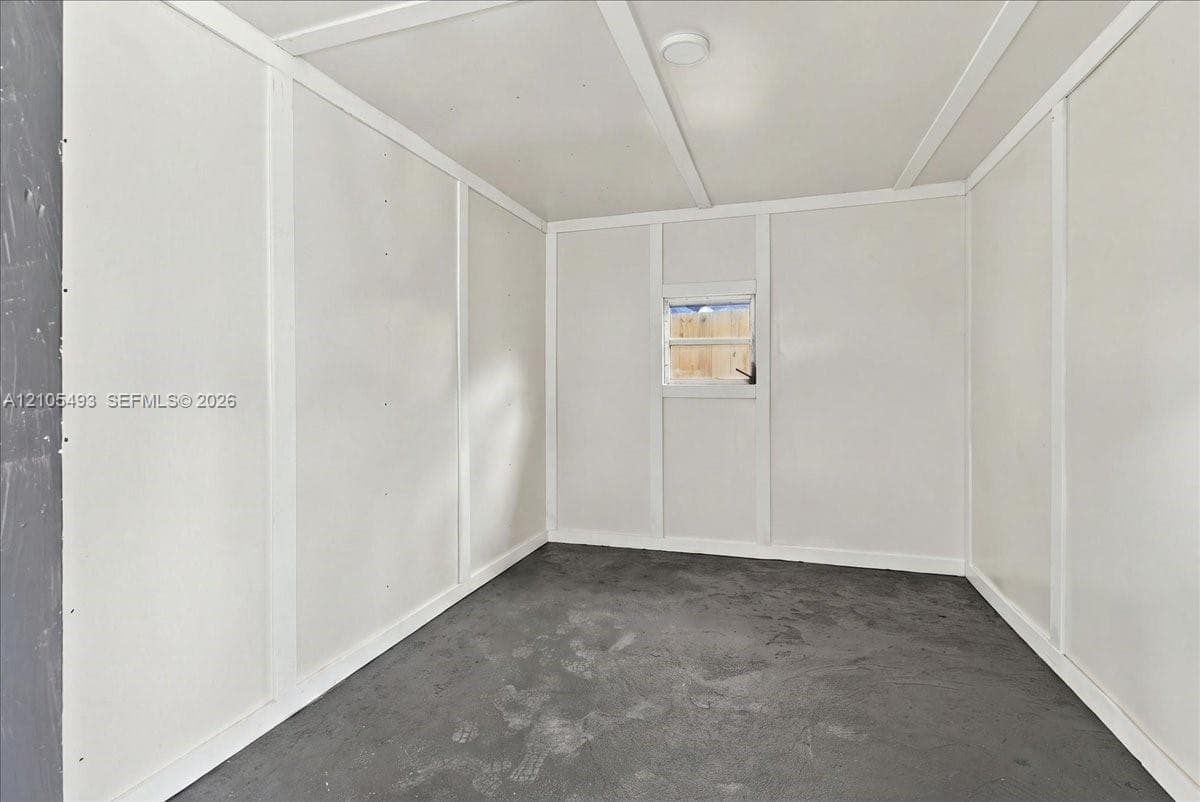 Interior space featuring smooth wall panels, vertical trim detailing, a recessed ceiling fixture, and a window