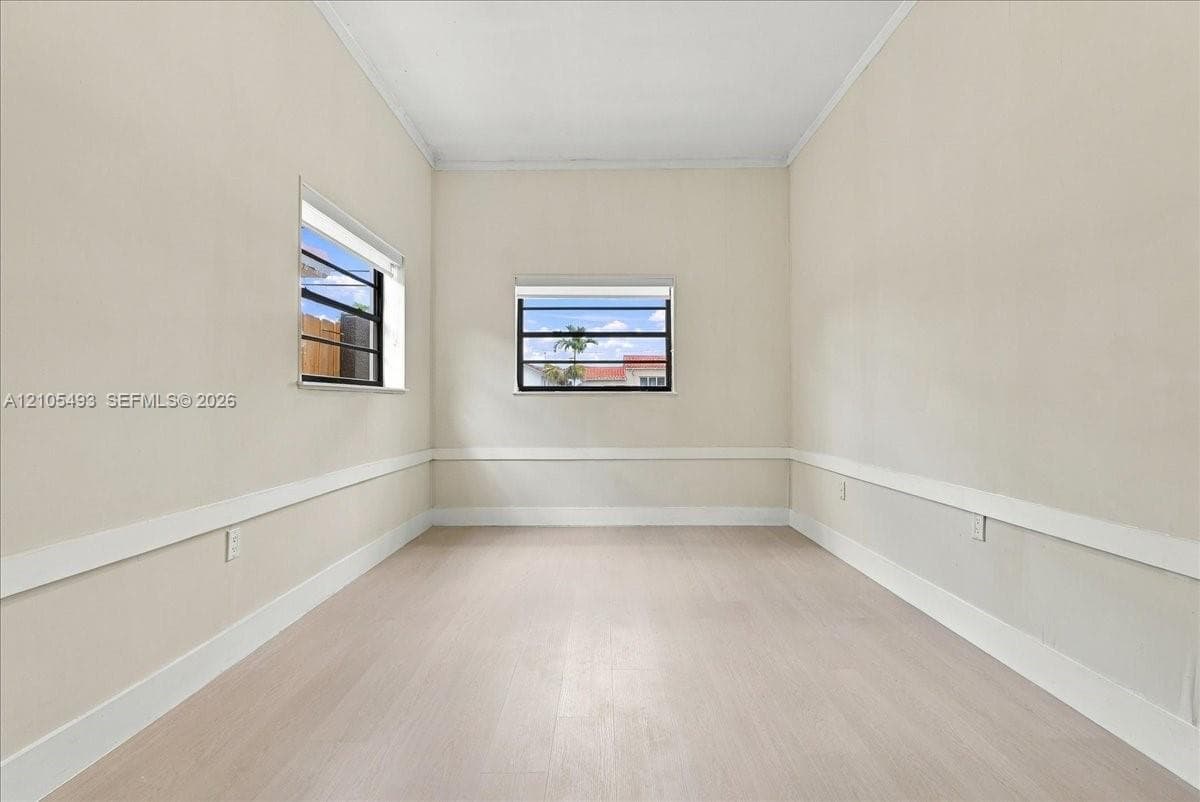 Neutral interior space featuring light-toned wood-finish flooring, white walls with chair rail molding, and horizontal sliding windows