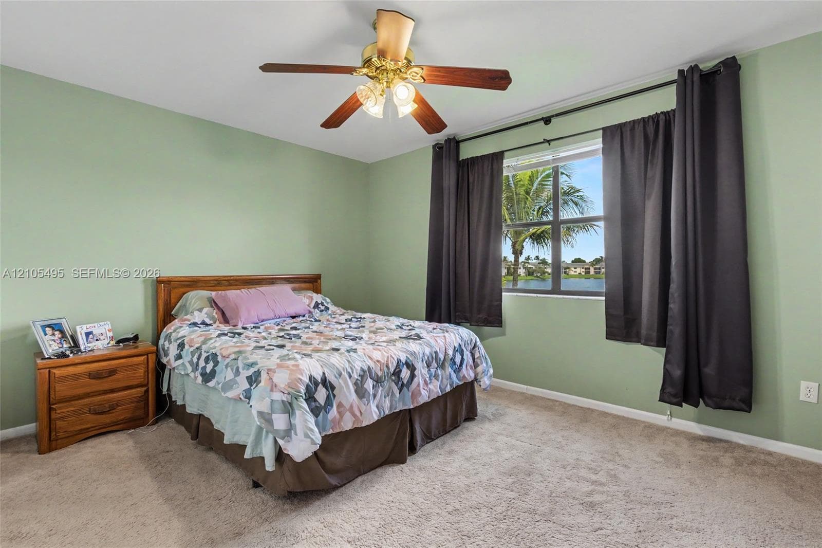 Bedroom interior featuring wall-to-wall carpeting, a ceiling fan with integrated lighting, and a window with exterior water frontage