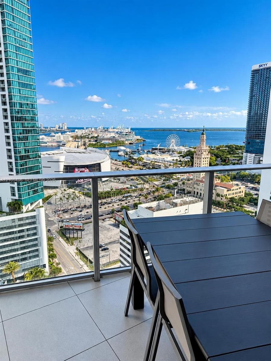Private balcony featuring large-format tile flooring and a glass railing, showcasing expansive cityscape and water scenery