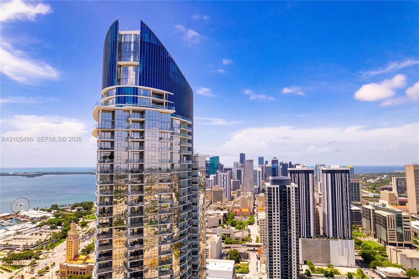 High-rise architectural structure featuring a glass-paneled facade, curved structural design, and multiple cantilevered balconies