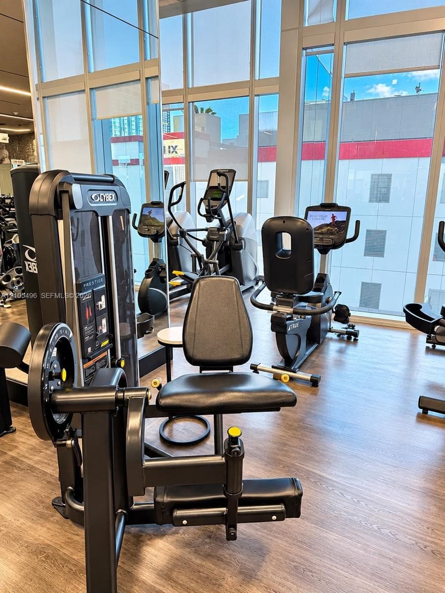 Fitness center featuring floor-to-ceiling windows, wood-finish flooring, and mirrored walls