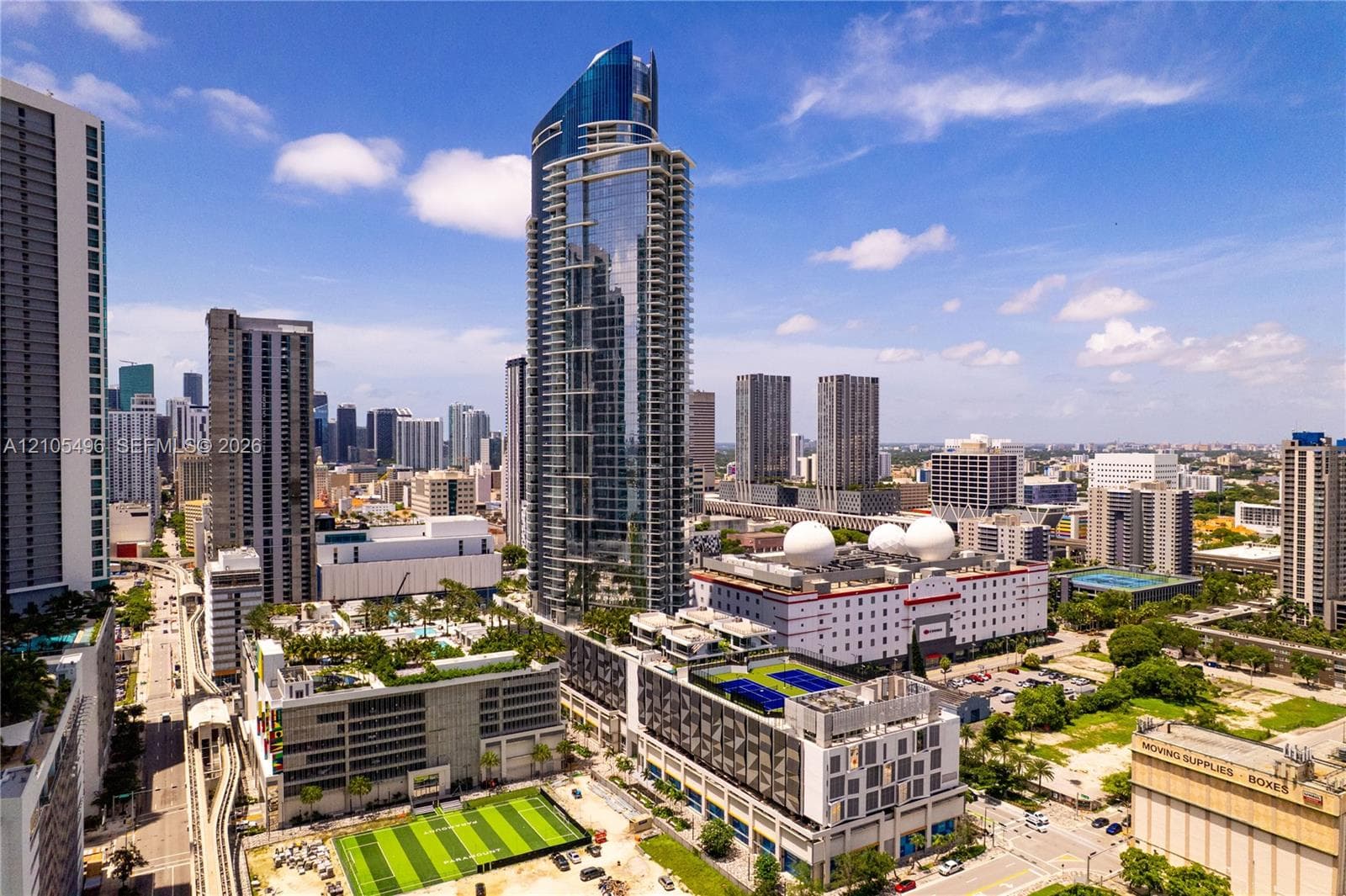 High-rise glass facade residential tower featuring wrap-around balconies and a multi-level base podium