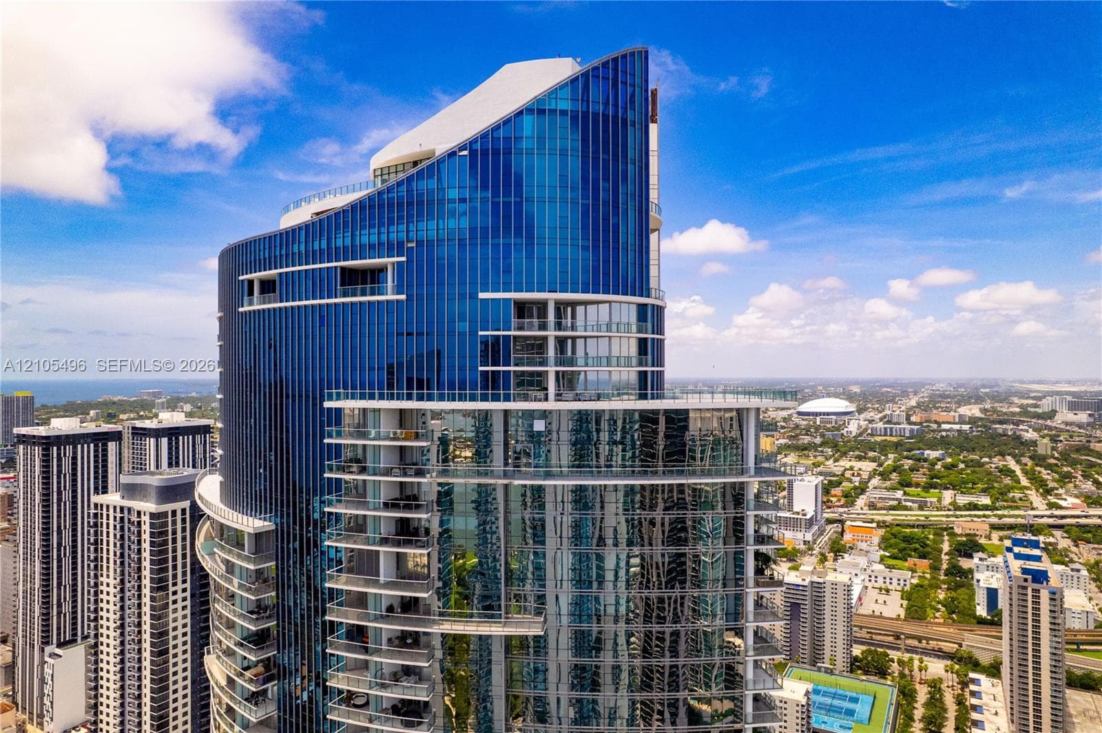 High-rise glass facade featuring floor-to-ceiling windows, wrap-around private balconies, and an angular architectural silhouette