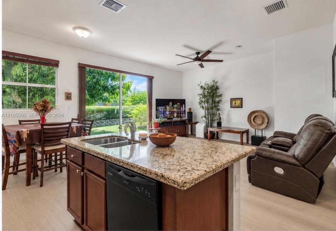 Kitchen island with granite countertop, double basin sink, and integrated dishwasher