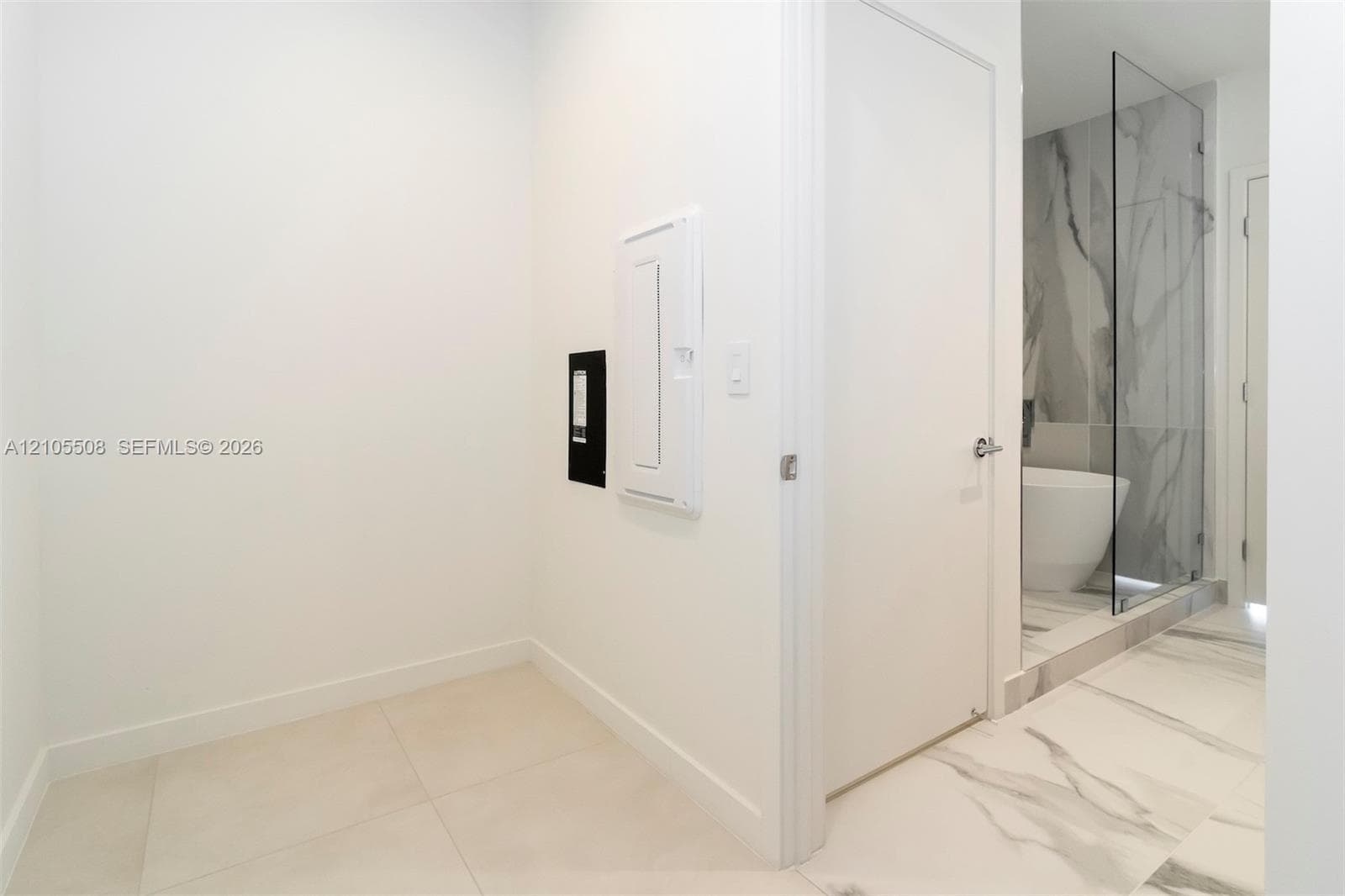 White interior walls, light-toned tile flooring, and a glass-enclosed shower with a marble-patterned tile surround