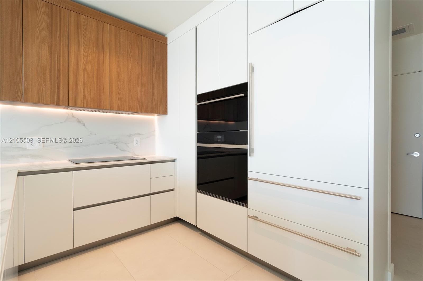 Wood-finish upper cabinetry, integrated appliances, built-in wall oven, induction cooktop, and quartz-finish countertops