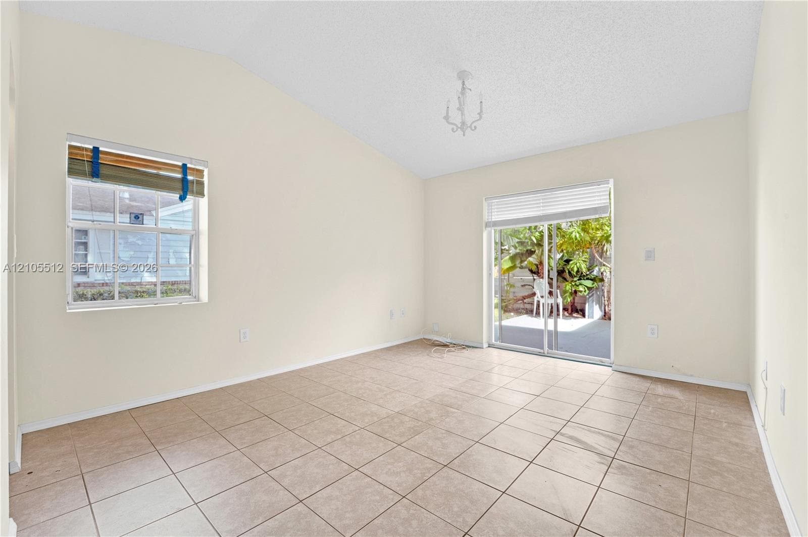 Vaulted ceilings, neutral wall finishes, tile flooring, and sliding glass doors providing outdoor access