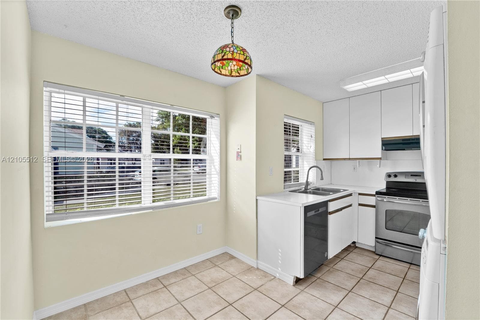 Interior area featuring high vaulted ceilings, large-format neutral tile flooring, sliding glass patio doors, and a multi-arm chandelier