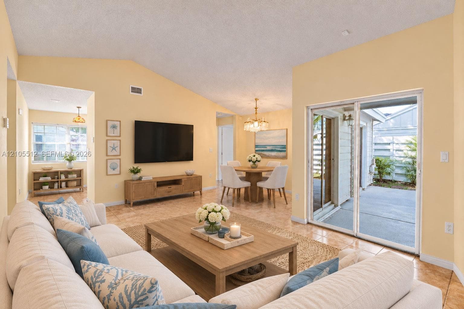 Vaulted ceiling with a central light fixture and neutral tile flooring