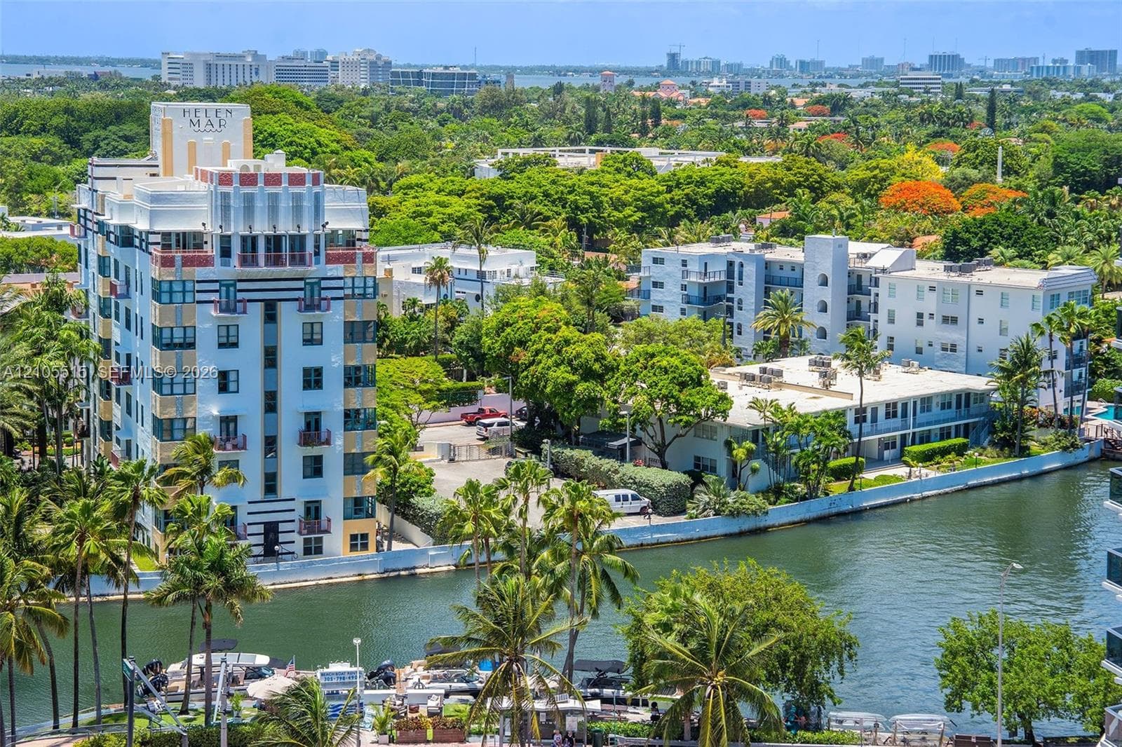 High-rise Art Deco architecture with multi-story facades, water frontage, mature palm trees, and dense urban canopy