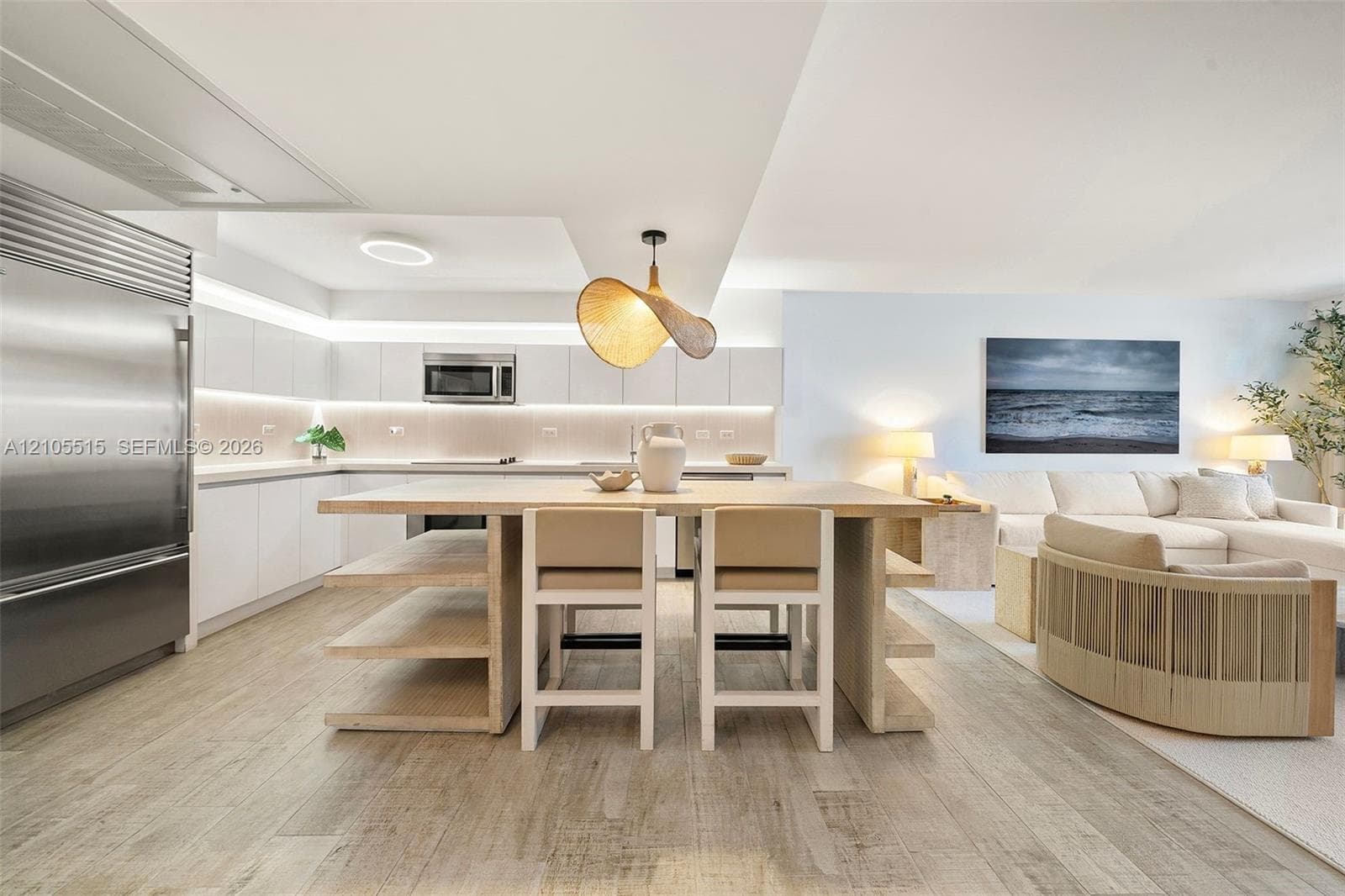 Kitchen featuring wood-finish flooring, white flat-panel cabinetry, stainless steel refrigerator, recessed lighting, and a kitchen island with built-in shelving