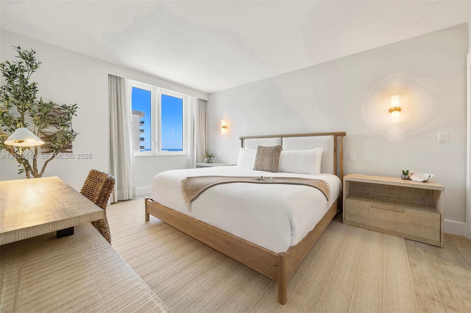 Wood-finish flooring, wall-mounted light fixtures, and dual-pane window set within a neutral-toned room