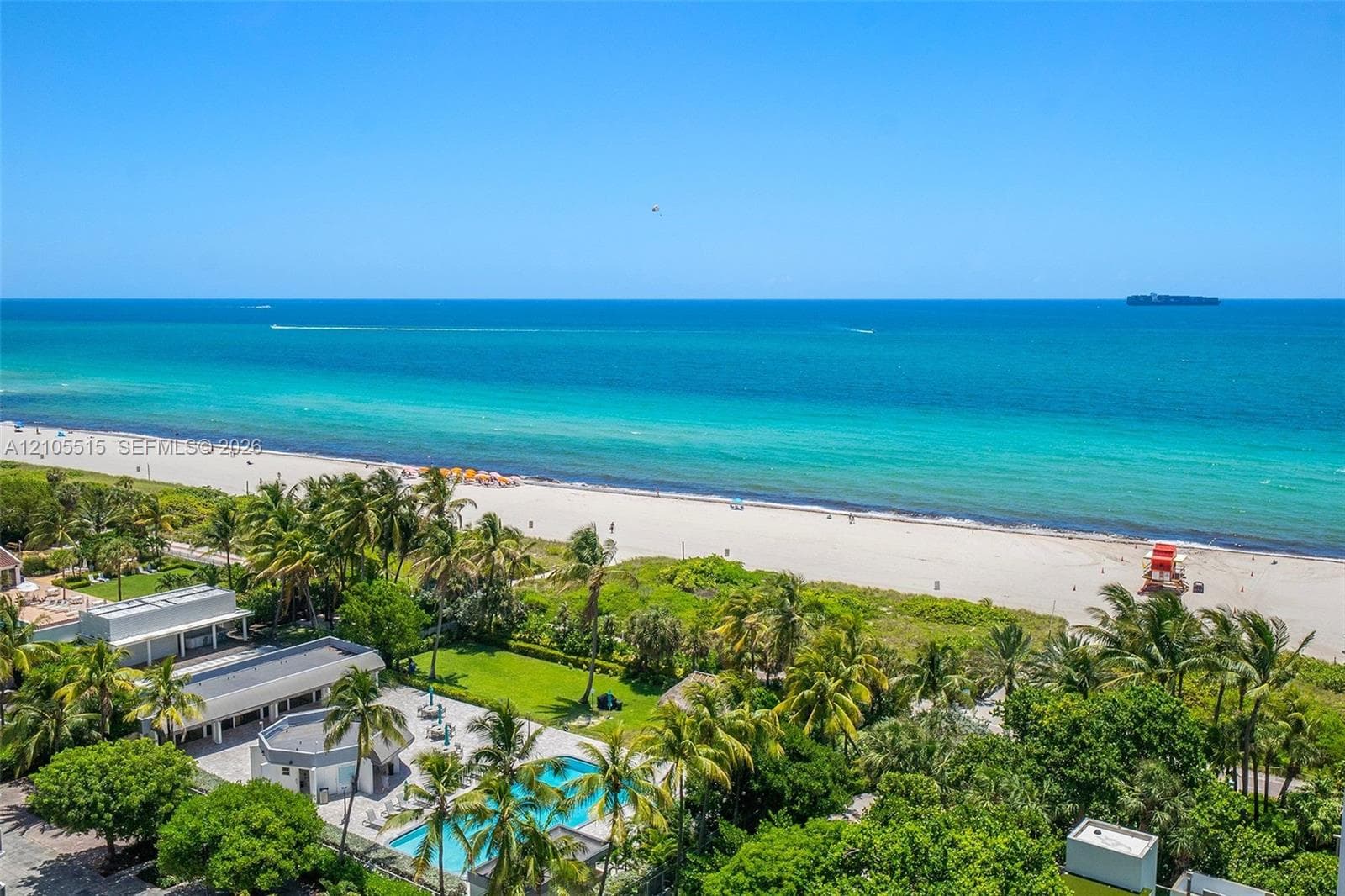 Oceanfront property featuring direct beach access, a private swimming pool, landscaped lawn, and mature palm trees