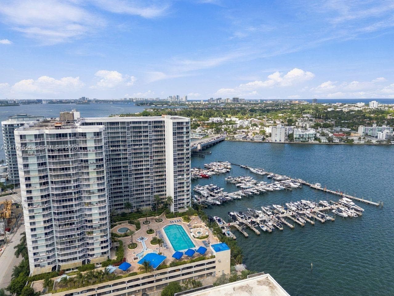 Waterfront high-rise building featuring a marina, outdoor swimming pool, and surrounding green spaces