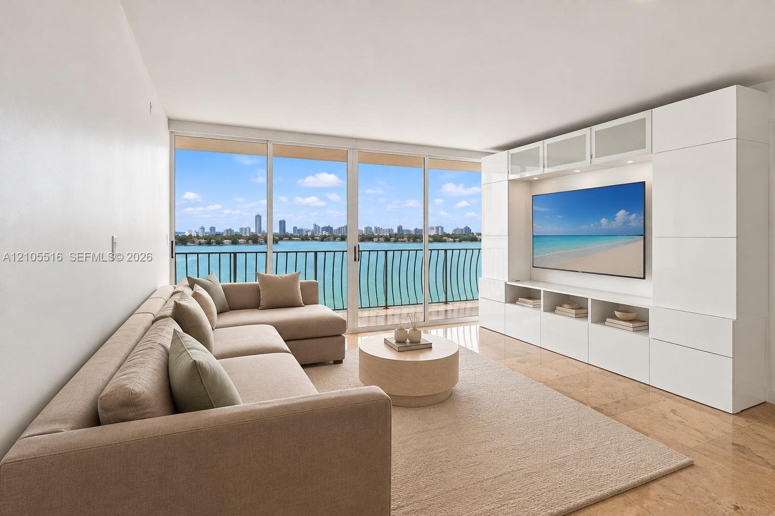 Large-format tile flooring, expansive sliding glass doors, built-in entertainment center, water scenery, and distant city skyline