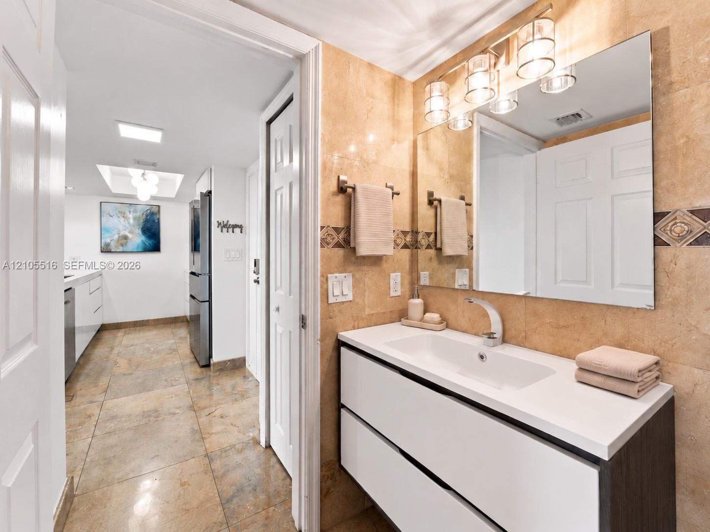 Floating vanity with integrated sink and white countertop, full-width mirror, and decorative wall lighting