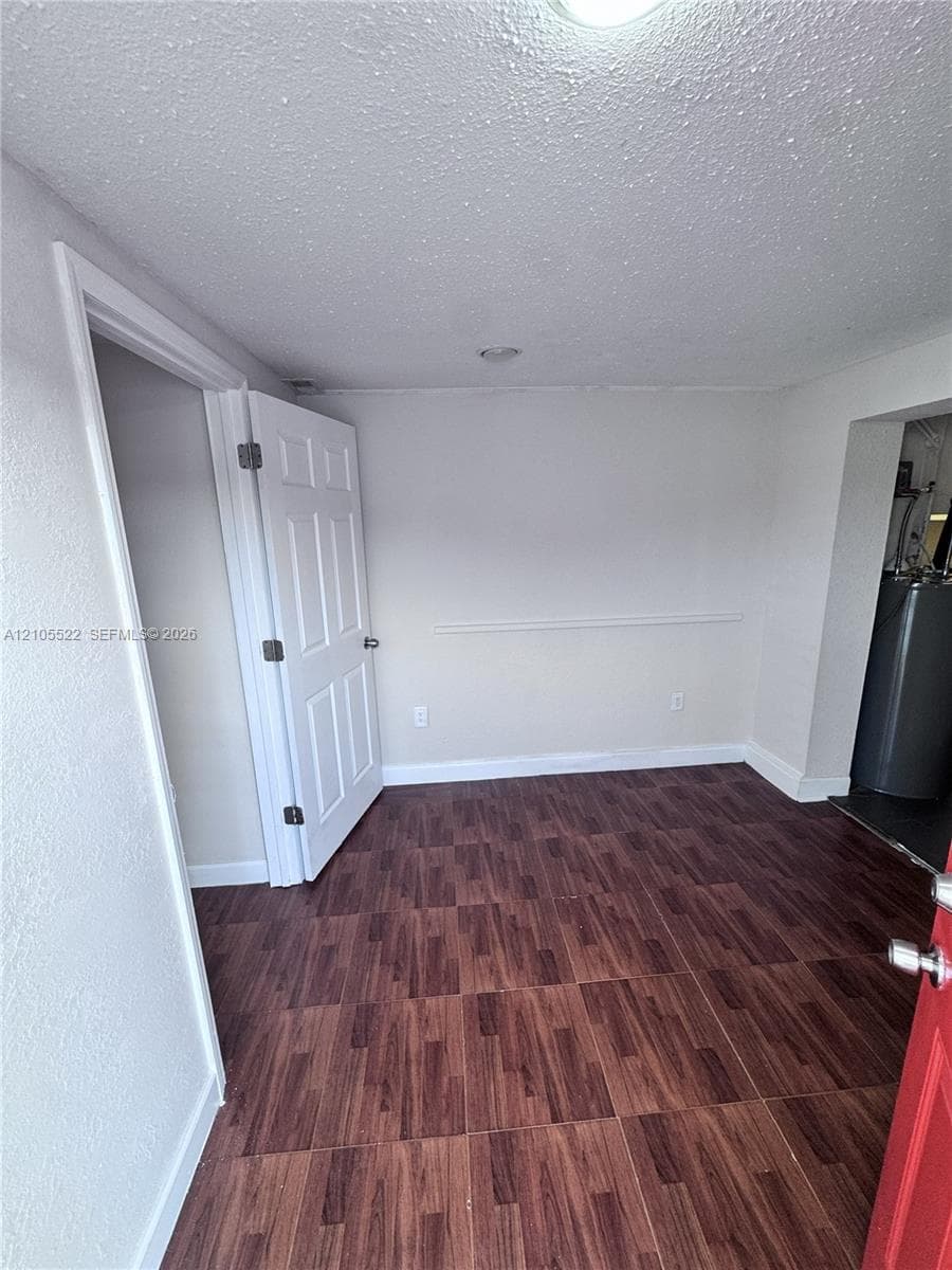 Wood-finish flooring, white trim, recessed lighting, and a white interior door