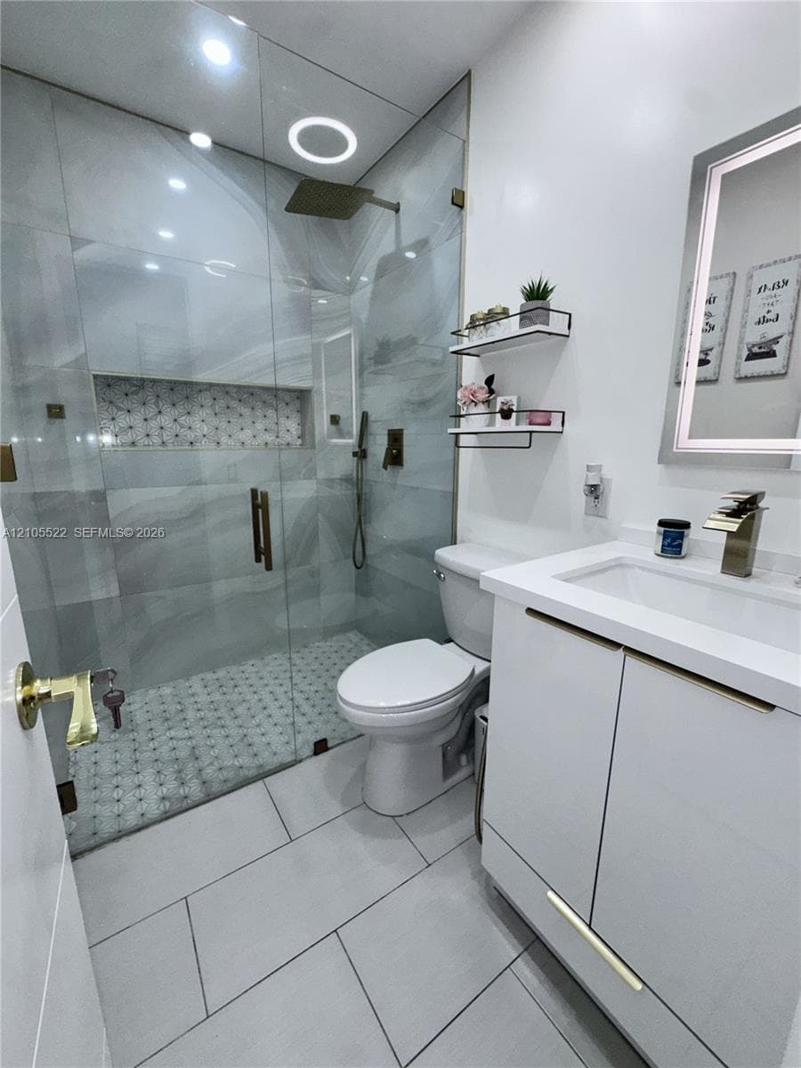 Glass-enclosed shower with a rainfall showerhead, integrated shower niche, and mosaic tile flooring