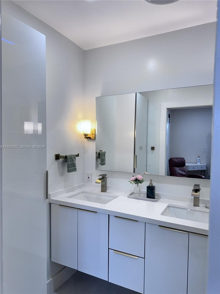 Double vanity with white cabinetry, integrated sinks, and polished chrome faucets
