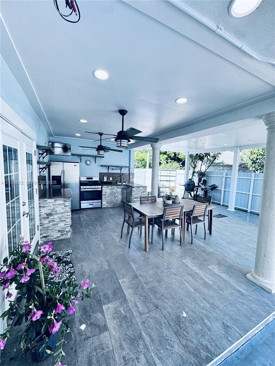 Covered patio featuring recessed lighting, ceiling fans, stone veneer kitchen island, and plank tile flooring