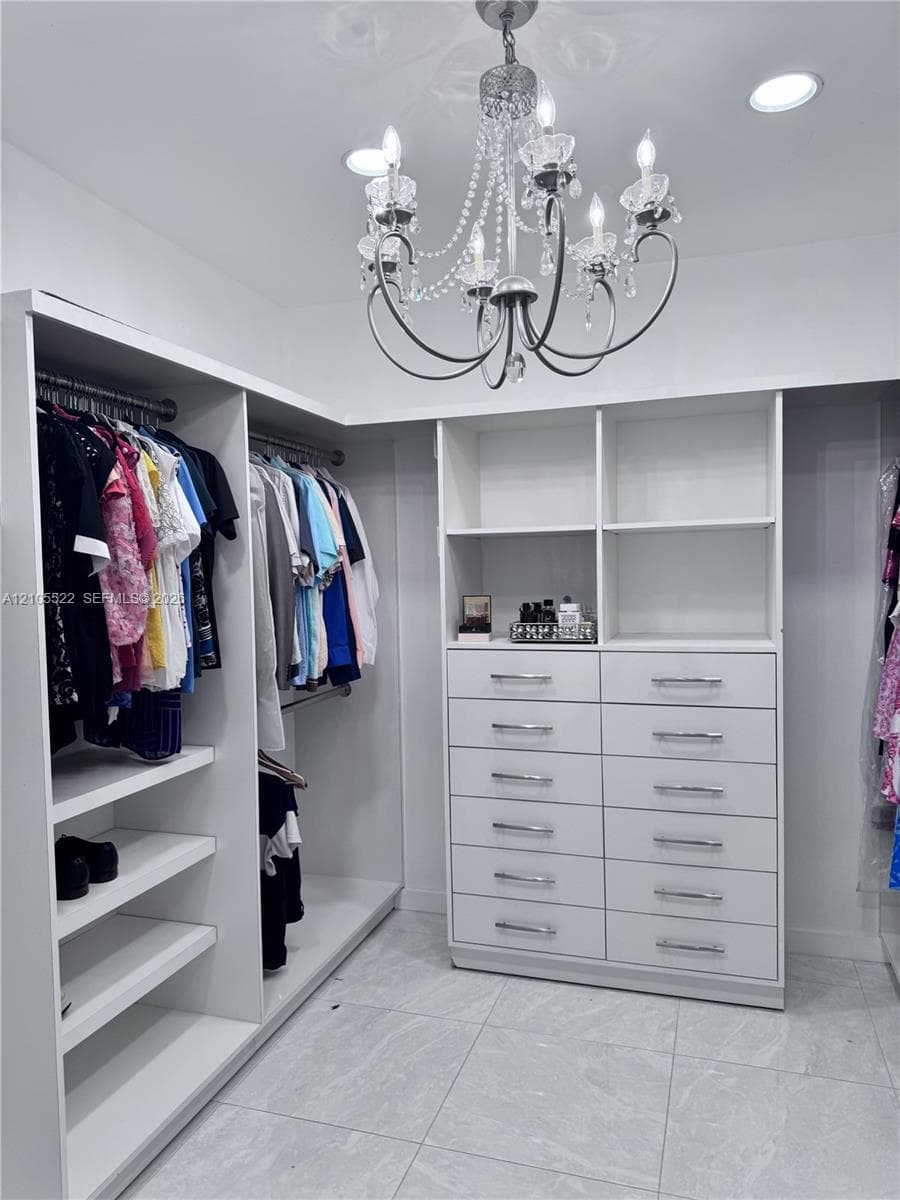 Built-in closet system featuring white shelving, multiple hanging rods, and an integrated dresser with chrome pulls
