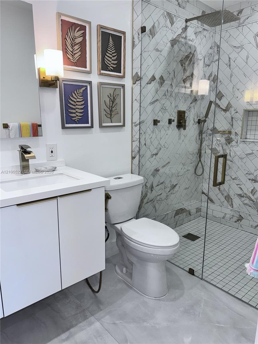 Walk-in shower with glass enclosure, herringbone tile, and rain shower head