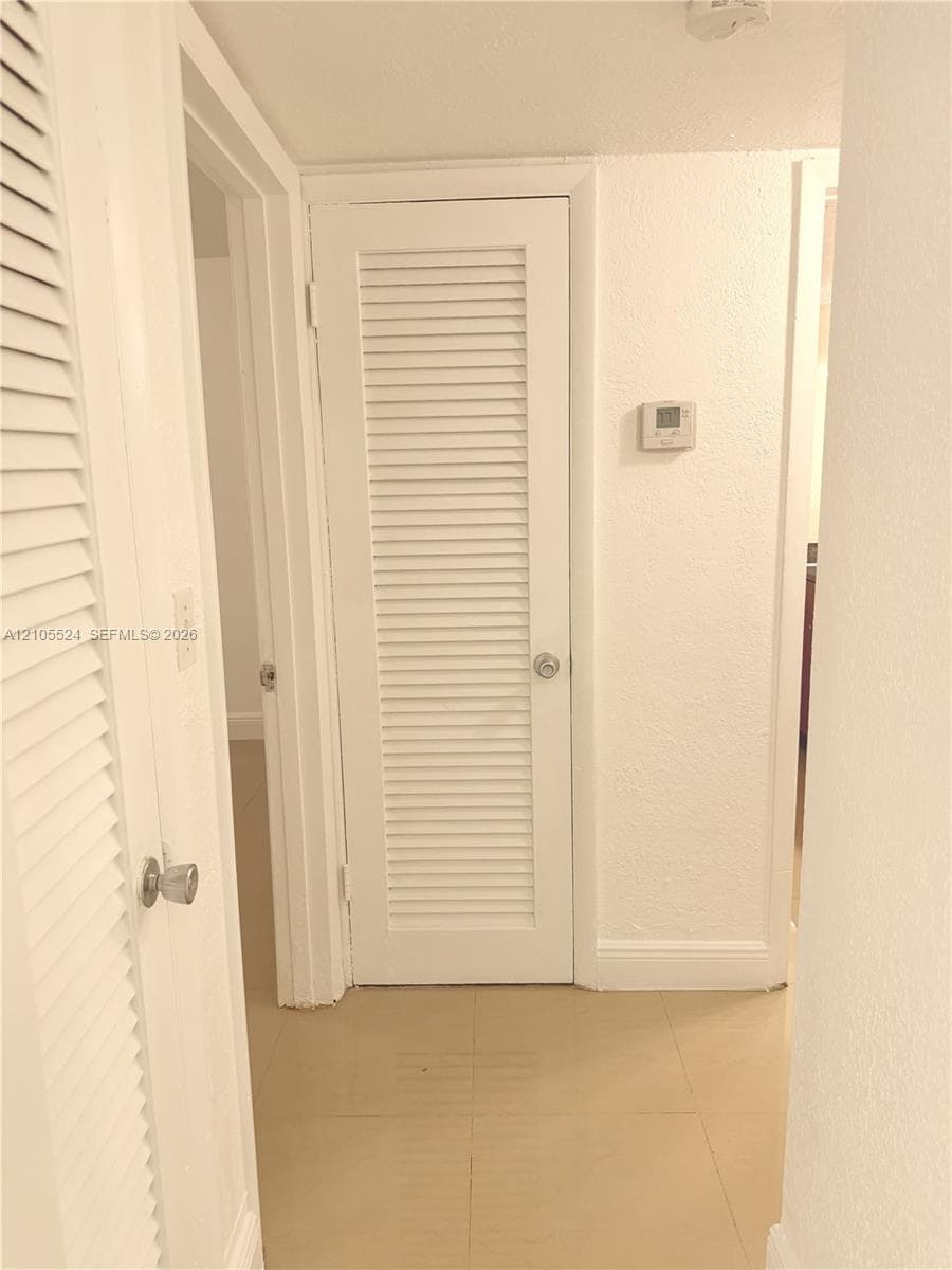 Recessed lighting, louvered doors, tile flooring, and a wall-mounted thermostat